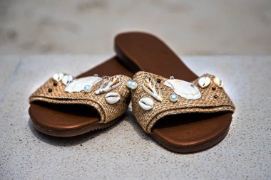 Sahilde el yapımı sandaletler. Çeşitli deniz salyangozları yerleştirilmiş.