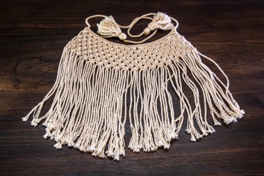 Beyaz örülmüş kolye, koyu ahşap bir masada el yapımı.