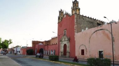 Kırsal kesimdeki Prehispanik Katolik kilisesi, önündeki caddenin önünden arabalar geçiyor, şafak vakti.