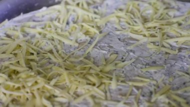 Metal rendeleyiciyle rendelemek ve pizza kabuklarının üzerine dökmek. Mutfakta Yemek Pişirme