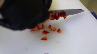 Beyaz bir kesme tahtasının üzerinde metal bir bıçakla sebzeleri doğramak. Mutfakta yemek pişirmek..