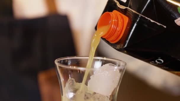 酒保在吧台准备鸡尾酒把橙汁倒入装有冰块的水晶玻璃中 用黑色手套在他手上拍特写 — 图库视频影像