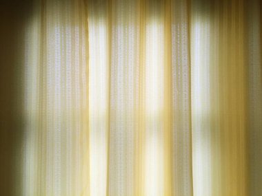 Açık kahverengi perdeler ve yumuşak, dışarıyı aydınlatır..