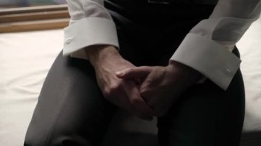 Erkek eli. Beyaz gömlekli bir adam oturur ve ellerini ovuşturur. Gergin bekliyor.