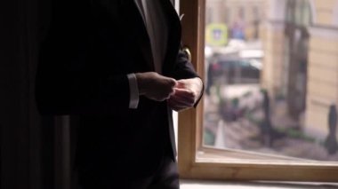 Genç bir adam smokin ceketini ilikliyor. Damat düğün ya da etkinlik için giyinir.