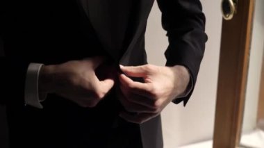Genç bir adam smokin ceketini ilikliyor. Damat düğün ya da etkinlik için giyinir.