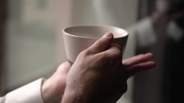 Mladý muž si dává šálek kávy, pije čaj nebo jiný nápoj. Detailní záběr hrnku — Stock video