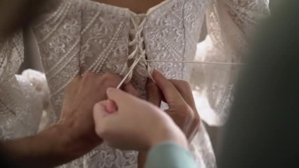Druhny wiążą i pomagają założyć suknię ślubną panny młodej. Poranne przygotowanie — Wideo stockowe