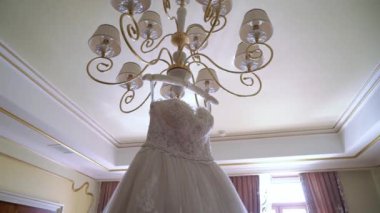 Gelinin beyaz gelinliği yatak odasında.