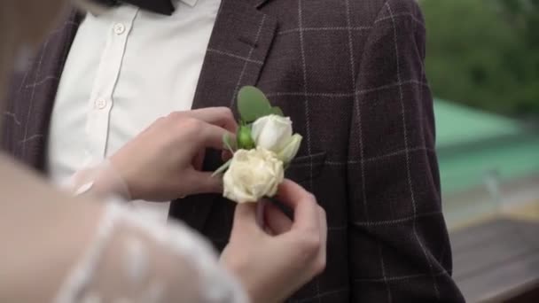 Невеста надела бутоньерку для жениха в день свадьбы, прекрасная пара — стоковое видео