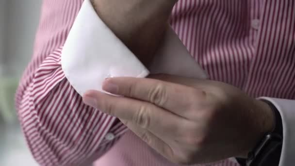 Молодой человек надевает запонки на белую рубашку. Жених одевается утром — стоковое видео
