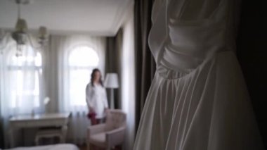 Gelinin beyaz gelinliği yatak odasında.