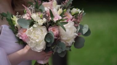 Gelin açık havada çiçek buketi tutuyor.
