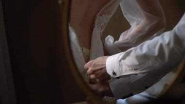 Damat kravatları ve gelinin gelinliğini giymesine yardım eder. Sabah hazırlığı.