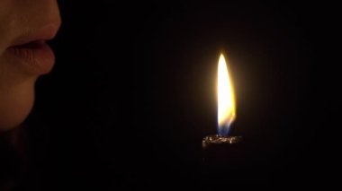 Kız karanlıkta mum ateşini söndürüyor. Kadın dudakları yakın çekim