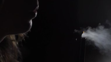 Kız karanlıkta mum ateşini söndürüyor. Kadın dudakları yakın çekim