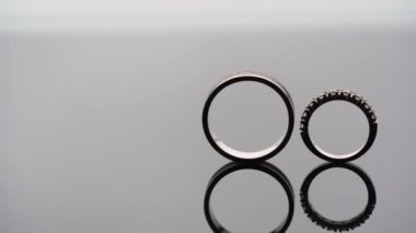 Üç alyans ve nişan takıları. Yüzük yuvarlanıyor.