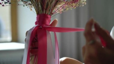Sabahleyin elinde pembe kırmızı kurdeleli bir buket çiçek tutan genç bir kız. Gelin