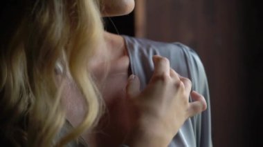 Gri ipek bornoz giymiş genç bir kadın.