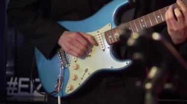 Gitarist adam konserde gitar çalıyor. Sahnede orkestra, müzik çalan müzisyen