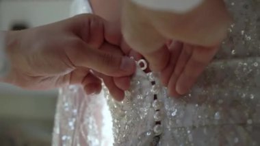 Damat kravatları ve gelinliklerin giyilmesine yardım ediyor. Gelinin beyaz elbisesiyle sabah hazırlığı. Fermuarını çek.