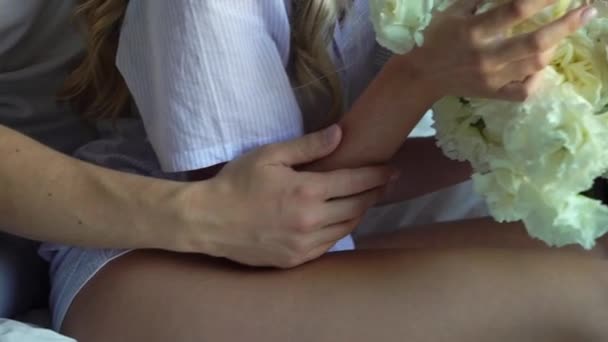 Junges Paar, das sich am Morgen umarmt und einen Blumenstrauß in der Hand hält. Braut mit Brautrosen und Pfingstrosen — Stockvideo