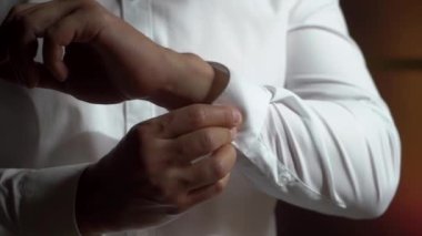 Düğmeleri ilikleyen genç adam beyaz gömlek giydi.