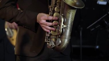 Saxophonist sahnede saksafon çalıyor. Konserde bando çalan saksafoncu.