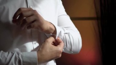 Düğmeleri ilikleyen genç adam beyaz gömlek giydi.