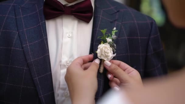 Nevěsta oblékla boutonniere pro svého ženicha ve svatební den, krásný pár. — Stock video