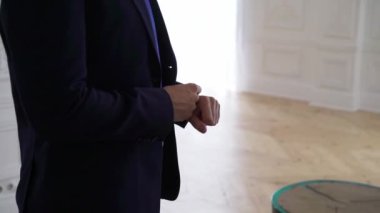 Takım elbiseli genç bir adam kol saati takıyor. Damat düğün ya da etkinlik için giyinir..