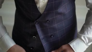 Genç bir adam smokin ceketini ilikliyor. Damat düğün ya da etkinlik için giyinir..