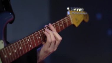 Gitarist adam konserde gitar çalıyor. Sahnede orkestra, müzik çalan müzisyen