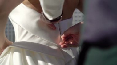 Damat kravatları ve gelinliklerin giyilmesine yardım ediyor. Gelinin beyaz elbisesiyle sabah hazırlığı. Fermuarını çek.