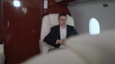 Uçakta birinci sınıf takım elbiseli, dizüstü bilgisayarı ve bir bardak şampanyası olan bir adam. Özel jetle lüks seyahat, iş adamı uçakları.