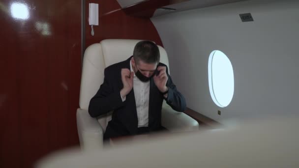Junger Mann im Anzug in der Business Class eines Flugzeugs, Geschäftsmann oder Manager im Privatjet mit medizinischer Schutzmaske Covid-19 Coronavirus Pandemie — Stockvideo