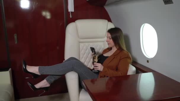 Woman passenger in airplane business first class with champagne. Luxury girl in private jet flight travel — Αρχείο Βίντεο