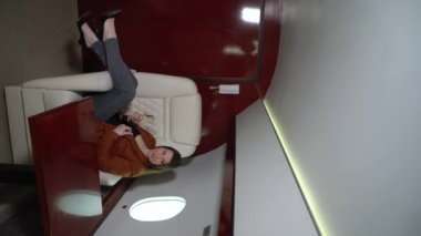 Vertical video. Woman passenger in airplane business first class with champagne. Luxury girl in private jet flight travel