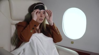 Woman sleeping in airplane, business first class. Luxury travel journey in private jet. Girl relaxing in mask