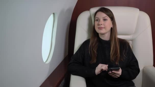 Woman in airplane with mobile phone, using smartphone in first business class or private jet, flight travel — Stok Video