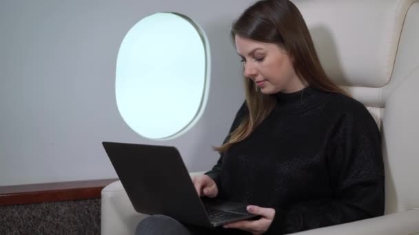 Mujer joven en avión volando, chica en jet privado o primera clase de negocios. Mujer de negocios con portátil y champán viajes de lujo — Vídeo de stock