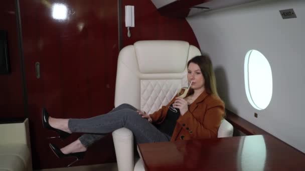 Woman passenger in airplane business first class with champagne. Luxury girl in private jet flight travel — стоковое видео