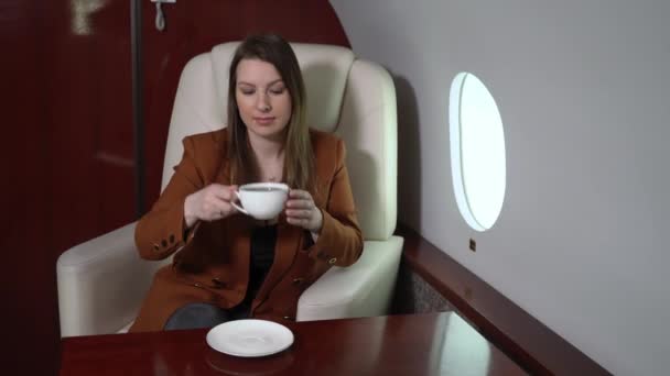 Woman in airplane cabin first business class drinking coffee. Passenger vip in private jet luxury travel — Stock Video