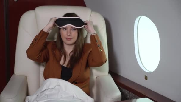 Woman sleeping in airplane, business first class. Luxury travel journey in private jet. Girl relaxing in mask — Stockvideo