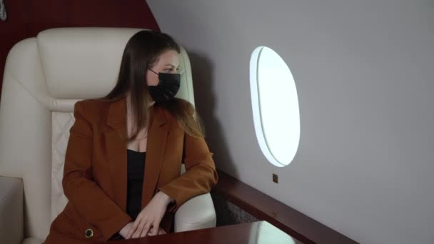 Young woman in suit flying airplane business class, businessman or manager in private jet flight wearing protective medical mask covid-19 coronavirus pandemic — Stockvideo