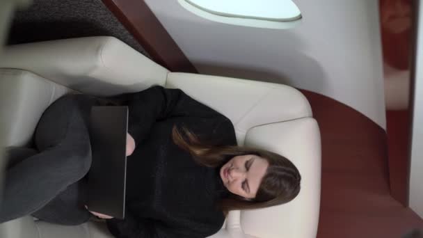 Verticale video. Jonge vrouw in het vliegtuig vliegen, meisje in prive-jet of eerste business class. Zakenvrouw met laptop en champagne luxe reizen — Stockvideo