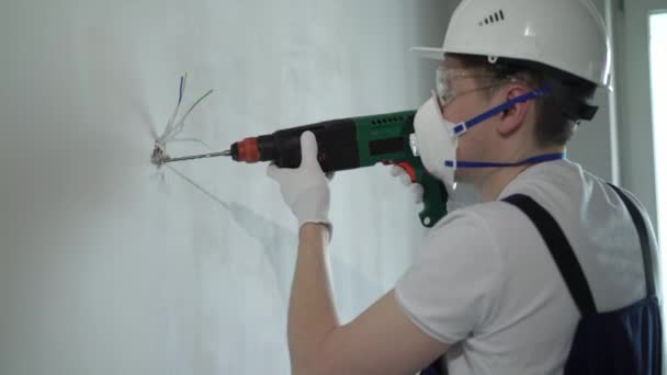 Un trabajador constructor en un sitio de construcción con un puñetazo hace reparaciones a un apartamento o una casa — Vídeos de Stock