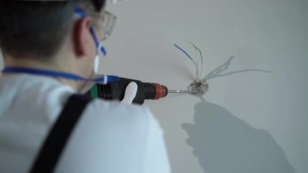 Um construtor de trabalhadores em um canteiro de obras com um soco faz reparos em um apartamento ou uma casa — Vídeo de Stock