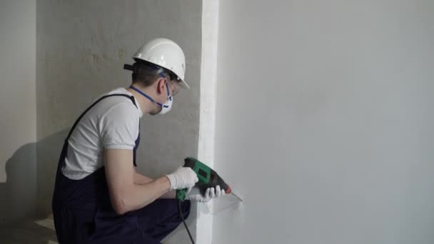 Рабочий строитель на строительной площадке с пуншем ремонтирует квартиру или дом — стоковое видео