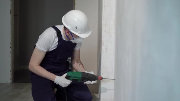 Un trabajador constructor en un sitio de construcción con un puñetazo hace reparaciones a un apartamento o una casa — Vídeos de Stock